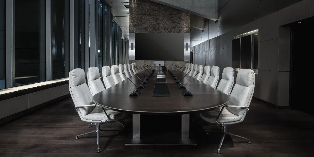 Modern boardroom with white chairs and dark oval table